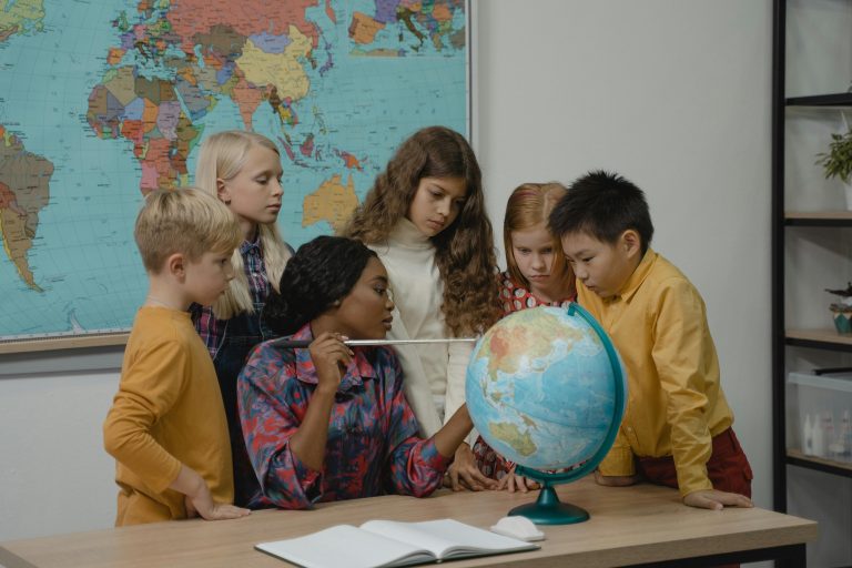5 kinderen en een juf bij een wereldbol (👶 Internationale Dag van de Rechten van het Kind – 20 november )
